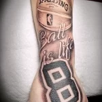 Фото тату на руке: баскетбольная кепка Spalding с надписью 'Ball is life' и номером 8, выполненная в черно-серой гамме.