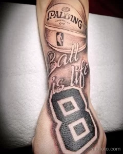 Фото тату на руке: баскетбольная кепка Spalding с надписью 'Ball is life' и номером 8, выполненная в черно-серой гамме.