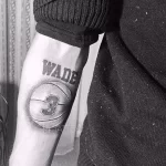 Фото тату на руке с изображением баскетбольного мяча, на котором написано имя "Wade" и номер "3", выполненное в черно-серых тонах.