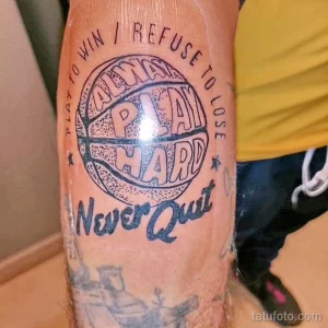 Фото татуировки с баскетбольным мячом и надписью 'Always Play Hard Never Quit', выполненной в синих и красных тонах на предплечье. Мотивационный рисунок.
