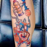 Фото тату с изображением персонажей Looney Tunes (Багз Банни, Даффи Дак, Таз) играющих в баскетбол. Цветная татуировка на руке, выполненная в мультяшном стиле.