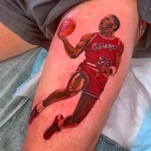 Фото тату: реалистичный портрет Майкла Джордана в красной форме Chicago Bulls, запечатленного в момент броска мяча. Татуировка выполнена на ноге.
