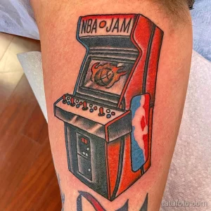 Фото тату на руке: красочное изображение игрового автомата NBA Jam в стиле ретро. Рисунок выполнен в ярких цветах с проработкой деталей.