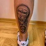 Фото тату на икре: красочный рисунок баскетбольного мяча Spalding с надписью 'Ball is life'. Детализированный эскиз татуировки.