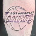 Фото тату логотипа баскетбольной команды Los Angeles Lakers на руке. Фиолетовый и золотой цвета, четкие линии.