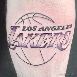 Фото тату логотипа баскетбольной команды Los Angeles Lakers на руке. Фиолетовый и золотой цвета, четкие линии.