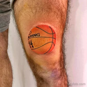 Фото тату реалистичного баскетбольного мяча Spalding с номером 14 на колене. Яркий оранжевый цвет и четкие линии.