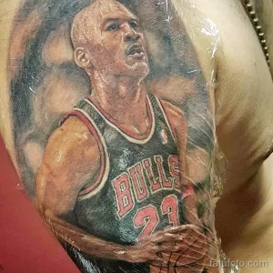 Фото тату на груди с изображением Майкла Джордана в форме Chicago Bulls, выполненное в реалистичном стиле с яркими цветами.
