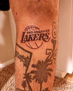 Фото тату на ноге с изображением логотипа Los Angeles Lakers, номера 24 Кобе Брайанта и пальм, выполненное в черном цвете в минималистичном стиле.