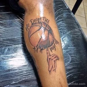 Фото татуировки на ноге с изображением баскетбольного мяча и надписи "No Days Off til it pays off". Рисунок выполнен в черно-серых тонах.
