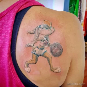Фото тату красочной Лолы Бани из Space Jam, играющей в баскетбол, выполненное на плече.