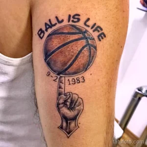 Фото тату на руке: надпись 'Ball is Life', баскетбольный мяч, рука, указывающая на мяч, черно-белый рисунок, реалистичный стиль.