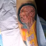 Фото татуировки на руке с ярким портретом Коби Брайанта в форме команды Lakers.