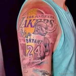 Фото татуировки с портретом Коби Брайанта и логотипом Los Angeles Lakers на плече. Рисунок выполнен в реалистичном стиле с использованием темных и ярких оттенков.