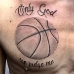 Фото тату на груди: реалистичный баскетбольный мяч с надписью "Only God can judge me". Черно-серые тона, каллиграфический шрифт, сильный посыл.