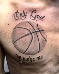 Фото тату на груди: реалистичный баскетбольный мяч с надписью "Only God can judge me". Черно-серые тона, каллиграфический шрифт, сильный посыл.