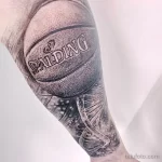 Фото тату реалистичного баскетбольного мяча Spalding на предплечье, выполненного в черно-серых тонах с высокой детализацией и эффектом объема.