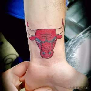 Фото тату с изображением головы быка, символа баскетбольной команды Chicago Bulls. Красный и черный рисунок, выполненный в минималистичном стиле.