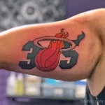 Фото тату с логотипом баскетбольной команды Miami Heat на руке. Красный и черный рисунок, выполненный в минималистичном стиле.