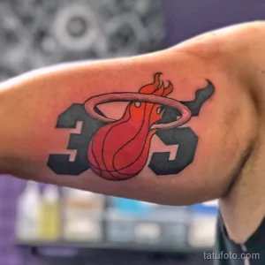 Фото тату с логотипом баскетбольной команды Miami Heat на руке. Красный и черный рисунок, выполненный в минималистичном стиле.