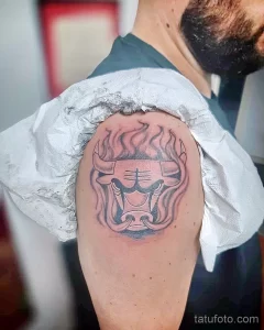 Фото тату с изображением головы быка в стиле blackwork, выполненное на плече. Татуировка отличается четкими линиями и контрастным затенением.