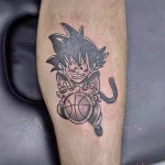 Фото тату с изображением аниме-персонажа Гоку из Dragon Ball Z на предплечье, выполненное в ярких цветах и четких линиях.