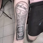 Фото татуировки на предплечье, изображающей баскетбольный мяч Spalding с номером 9 и надписью "Ball is life". Символизирует страсть к баскетболу и преданность игре.