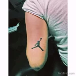 Черно-белое фото тату на руке с изображением логотипа Jumpman (силуэт Майкла Джордана в прыжке).