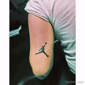 Черно-белое фото тату на руке с изображением логотипа Jumpman (силуэт Майкла Джордана в прыжке).