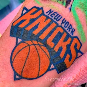 Цветное фото тату на плече с изображением логотипа баскетбольной команды New York Knicks и баскетбольного мяча.