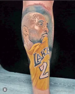 Фото тату на руке с реалистичным портретом Kobe Bryant в желтой форме Lakers с номером 24. Детализированный рисунок татуировки.
