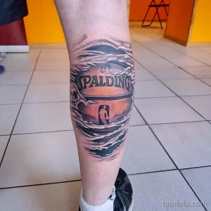 Фото тату на колене с изображением баскетбольного мяча Spalding, с автографом и эффектом трещин. Реалистичный рисунок татуировки.