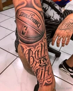 Фото тату на предплечье с изображением баскетбольного мяча Spalding и надписью 'Ball is Life' в реалистичном стиле.
