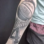 Фото тату баскетбольного мяча Spalding с надписью "NBA" и номером "4". Черно-белый рисунок татуировки на руке.