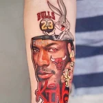 Фото тату на руке, изображающее Майкла Джордана в форме Chicago Bulls и мультяшного персонажа Багза Банни. Цветной рисунок татуировки.