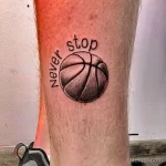 Фото тату на икре: баскетбольный мяч с надписью 'Never Stop'. Черно-белый рисунок татуировки в минималистичном стиле.
