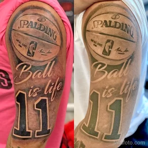 Фото татуировки на плече: логотип Spalding, надпись 'Ball is life' и баскетбольный мяч. Черно-серые тона, реалистичный стиль.