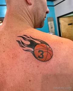 Фото тату баскетбольного мяча, охваченного пламенем, на плече. Яркий оранжевый и черный цвета.
