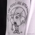 Фото тату баскетбольного мяча с лицом и надписью "Limits like fears are often illusions" на руке.