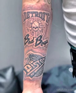 Черно-белое фото татуировки с изображением логотипа Detroit Bad Boys, включающего баскетбольный мяч, череп и надпись, выполненное на руке.