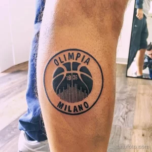 Фото тату на ноге с изображением логотипа баскетбольного клуба Olimpia Milano. Простой, лаконичный рисунок в черном цвете.