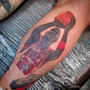 Фото тату с изображением Майкла Джордана в красной форме Chicago Bulls, запечатленного в момент броска мяча. Детализированный рисунок на предплечье.