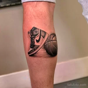 Фото тату на ноге с изображением кроссовка Air Jordan и баскетбольного мяча, выполненное в реалистичном черно-сером стиле.