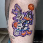 Яркое фото тату с изображением Багза Банни и Даффи Дака из мультфильма Space Jam, держащих баскетбольный мяч. Мультяшный стиль и насыщенные цвета.
