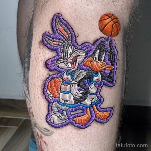 Яркое фото тату с изображением Багза Банни и Даффи Дака из мультфильма Space Jam, держащих баскетбольный мяч. Мультяшный стиль и насыщенные цвета.