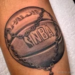 Фото тату баскетбольного мяча Spalding с логотипом NBA, выполненное в черно-серых тонах. Детализированный рисунок с цепью.