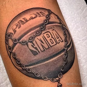 Фото тату баскетбольного мяча Spalding с логотипом NBA, выполненное в черно-серых тонах. Детализированный рисунок с цепью.