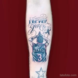 Фото тату на руке: портрет Аллена Айверсона в форме игрока, с надписью 'Never Give Up'. Черно-белый рисунок татуировки.