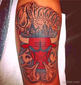 Фото тату на руке с изображением головы быка, символа Chicago Bulls, на фоне городского пейзажа Чикаго. Яркий и детализированный рисунок татуировки.