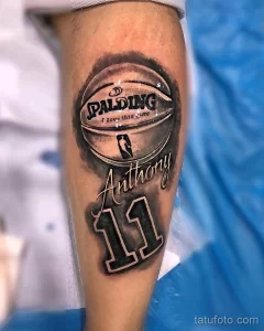 Фото татуировки на предплечье с изображением баскетбольного мяча Spalding и надписью 'Anthony 11'. Стильный и персонализированный дизайн.
